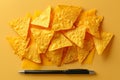 Triangular nacho chips and cheese slices on yellow background with pen Royalty Free Stock Photo