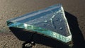 A triangular piece of broken glass lies on a textured asphalt Royalty Free Stock Photo