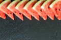 Triangular pieces of water melon arranged in line on black with copy space Royalty Free Stock Photo