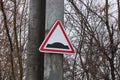 Triangular road sign speed bump on a concrete pillar among tree branches Royalty Free Stock Photo