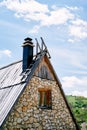 Triangular roof of a stone house with stairs and chimney against a cloudy sky