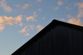 Triangle rooftop of corrugated steel building against blue sky with white fluffy clouds Royalty Free Stock Photo