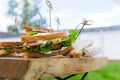 Triangular shaped sandwich with ham, vegetables and mayonnaise on a wooden platter. Menu for an outdoor event in summer