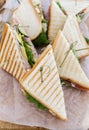 Triangular shaped sandwich with ham, vegetables and mayonnaise on a wooden platter. Menu for an outdoor event in summer