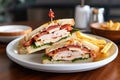 triangular sliced chicken club sandwich on a ceramic plate