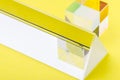 Triangular and square bright glass prism on yellow background