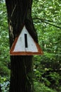 Triangular traffic sign, which over the years has grown together with a tree Royalty Free Stock Photo