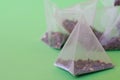 Triangular translucent pyramid tea bags with tea on a green background. The drink of long-livers. Photo. Macro. Selective focus Royalty Free Stock Photo