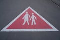 Triangular warning sign on the paved road showing walking pedestrians Royalty Free Stock Photo