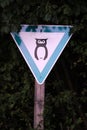 White and green triangular sign of owl surrounded by leaves in n nature