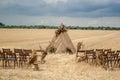 A triangular wooden arch decorated with flowers stands gracefully in a golden, mown field under the dramatic summer sky Royalty Free Stock Photo