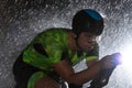 A triathlete braving the rain as he cycles through the night, preparing himself for the upcoming marathon. The blurred