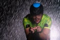 A triathlete braving the rain as he cycles through the night, preparing himself for the upcoming marathon. The blurred