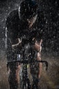 A triathlete braving the rain as he cycles through the night, preparing himself for the upcoming marathon. The blurred