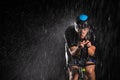 A triathlete braving the rain as he cycles through the night, preparing himself for the upcoming marathon. 