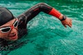 A triathlete in a professional swimming suit trains on the river while preparing for Olympic swimming Royalty Free Stock Photo