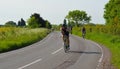 Triathletes on road cycling stage of triathlon fields and trees in background. Royalty Free Stock Photo