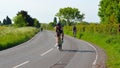 Triathletes on road cycling stage of triathlon fields and trees in background. Royalty Free Stock Photo