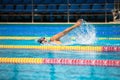 Athletic man swimming in front crawl style in the swimming pool with clear blue water.