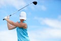 The trick is to keep your head down. A young female golfer swinging a golf club & x28;driver& x29; over her head about to Royalty Free Stock Photo