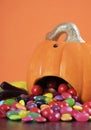 Trick or treat candy spilling out of Halloween pumpkin - vertical closeup.