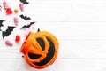 Trick or treat. Halloween candy spilled from jack o lantern bucket with skulls, black bats, ghost, spider decorations on white Royalty Free Stock Photo