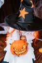 Trick or treat. Little child in witch hat taking candies out of Halloween pumpkin bucket. Royalty Free Stock Photo