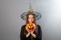 Trick or treat,witch teenager,happy Halloween,girl with a pumpkin candy bowl on a grey background,holiday evening of all saints