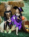 Trick-or-treating. Halloween Scene with cute children. Happy children with skeleton and witch costume holding and eating