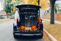 Trick or trunk. Black car trunk decorated for Halloween. Autumn fall decor with red pumpkins and yellow leaves for traditional