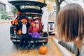 Trick or trunk. Children boy and girl with red pumpkins celebrating October Halloween holiday in trunk of car outdoors. Mother