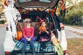 Trick or trunk. Children siblings sisters celebrating Halloween in trunk of car. Friends kids girls preparing for October holiday