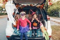 Trick or trunk. Children siblings sisters celebrating Halloween in trunk of car. Friends kids girls preparing for October holiday