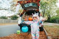 Trick or trunk. Happy baby in unicorn costume celebrating Halloween in trunk of car. Cute smiling toddler preparing for October