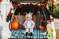 Trick or trunk. Sad upset baby in unicorn costume celebrating Halloween in trunk of car. Cute toddler celebrating October holiday