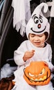 Trick or trunk. Trunk or treat. Little child in ghost costume celebrating Halloween party eating candies in decorated trunk of car Royalty Free Stock Photo