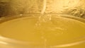 A trickle of thick golden honey flowing into a glass. Close up macro shot of honeyed molasses dripping in a glass full