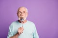 Tricky funny pensioner hold spoon in mouth joking look empty space wear blue t-shirt isolated on violate color