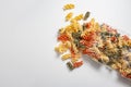 Tricolor Italian Fusilli pasta package opened with noodles spilling out of the package on a white surface. Concept foods rich in