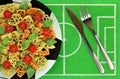 Tricolor pasta in form of football boots, balls, cups, green basil, red cherry tomato on plate like soccer ball. Royalty Free Stock Photo