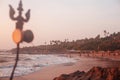 Trident totem near Shiva Face Rock Carving on Vagator Beach, Goa, India. Beautiful sunset and shore background. Northernmost beach Royalty Free Stock Photo