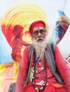 Tried sadhu sited on the bank of the river Ganges prior to Gangasagar yatra with a background of poster