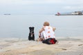 Trieste, September 5 2017, Italy: an adult woman sitting on a stone pier with two dogs