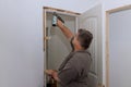 A trim carpenter installs interior doors in a newly constructed house as part of the construction process