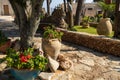 Trimmed lawns, potted geraniums, stone fences, palms and succulents