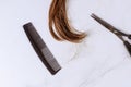 Trimmed of long brown female hair, scissors and comb