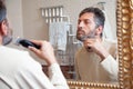 Man cuts beard in front of large mirror Royalty Free Stock Photo