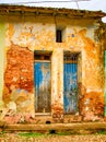 Pair of faded blue doors behind locked grate on brick wall with