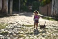 Trinidad, Cuba, August 16th, 2018: Little girl playing with her dog on the street of Trinidad