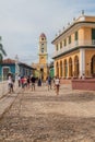 TRINIDAD, CUBA - FEB 8, 2016: Tourists walk on a cobbled street in the center of Trinidad, Cuba. Bell tower of Museo